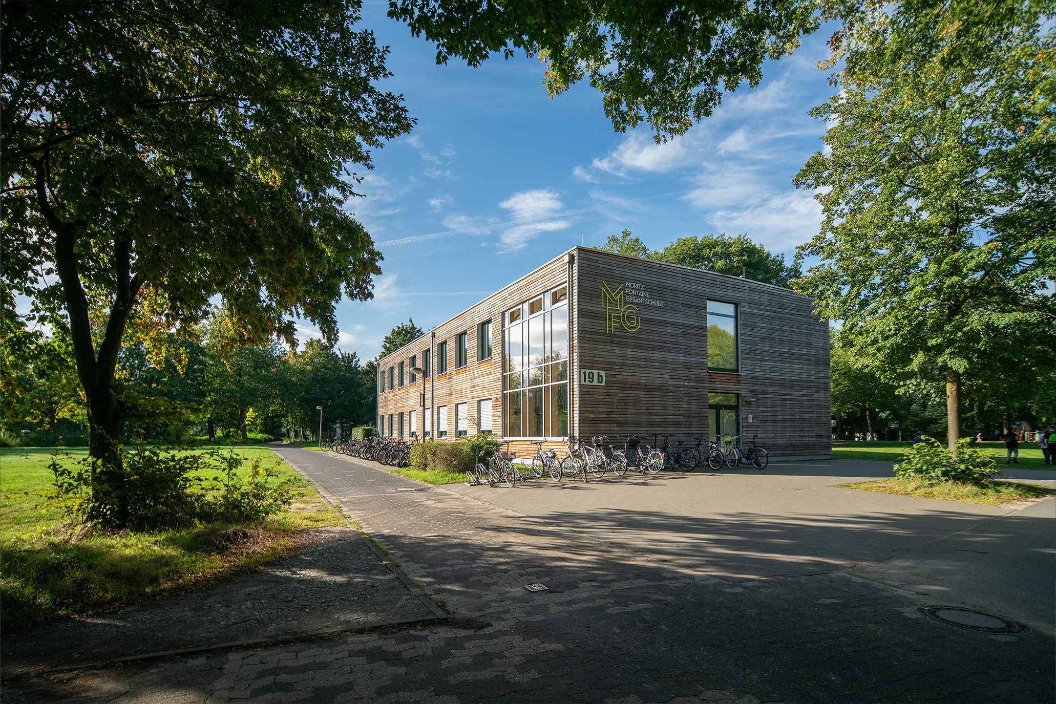 Moritz-Fontaine Gesamtschule: modernes Schulgebäude mit Fahrradständer und Bäumen im Hintergrund.