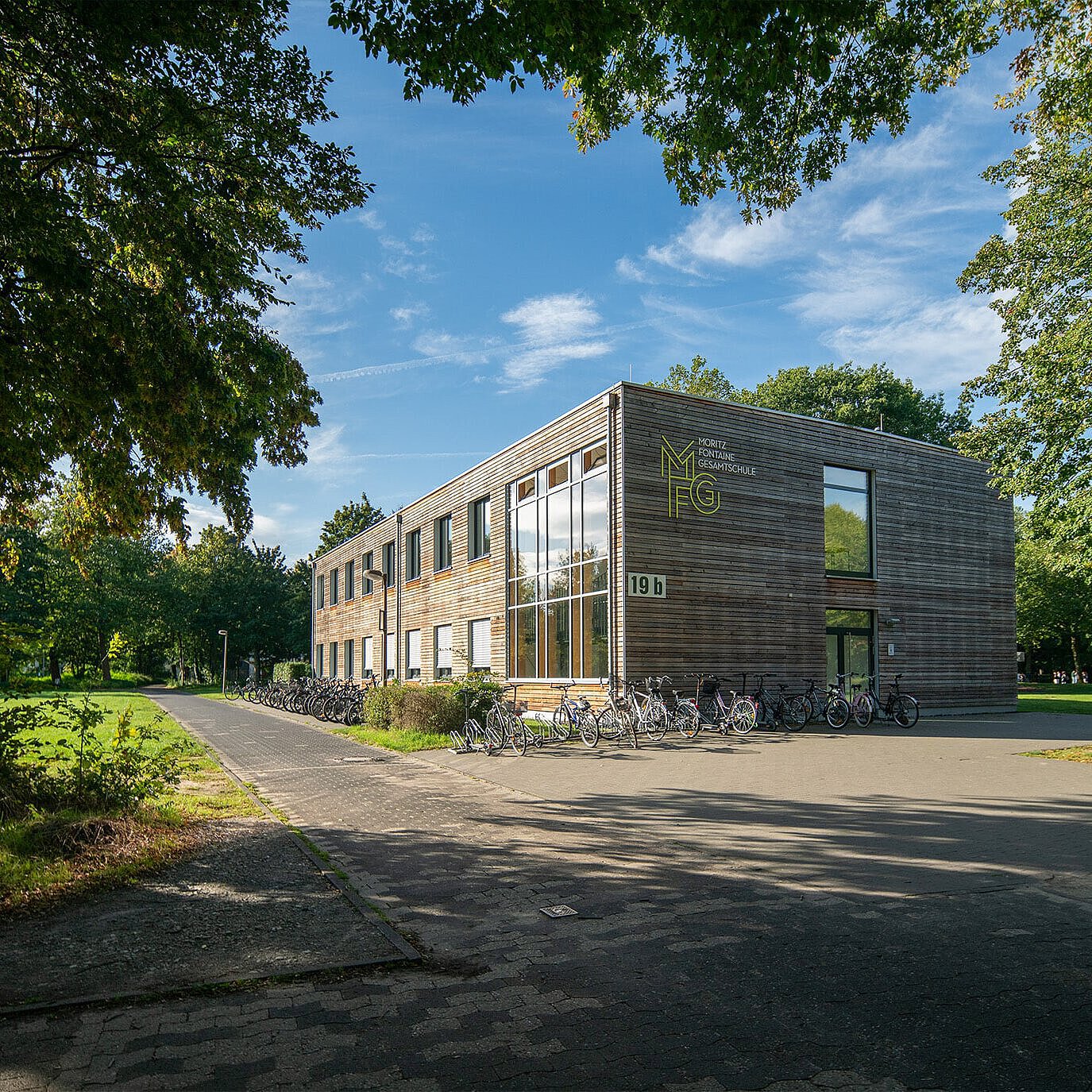 Moritz-Fontaine Gesamtschule: modernes Schulgebäude mit Fahrradständer und Bäumen im Hintergrund.